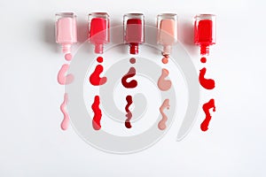 Spilled colorful nail polishes and bottles on white background