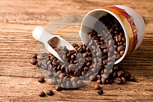 Spilled cup full of coffee grains on wooden board