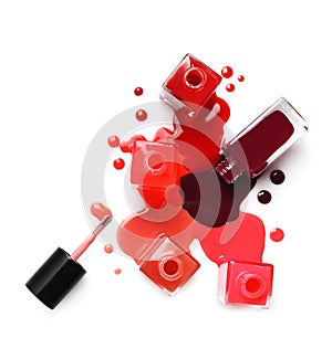 Spilled different nail polishes with bottles on white background