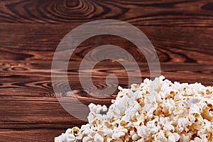 Spilled on the edges of popcorn on a wooden brown background