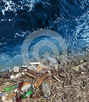 Spilled garbage on the beach of the big city. Empty used dirty plastic bottles. Dirty sea. Environmental pollution.