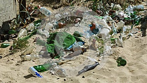 Spilled garbage on beach of big city. Empty used dirty plastic bottles. Dirty sea sandy shore Black Sea. Environmental pollution.