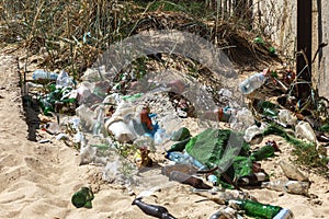 Spilled garbage on beach of big city. Empty used dirty plastic bottles. Dirty sea sandy shore Black Sea. Environmental pollution.