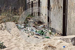 Spilled garbage on beach of big city. Empty used dirty plastic bottles. Dirty sea sandy shore Black Sea. Environmental pollution.