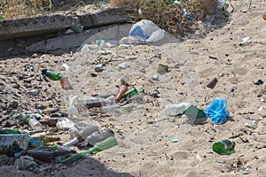 Spilled garbage on beach of big city. Empty used dirty plastic bottles. Dirty sea sandy shore Black Sea. Environmental pollution.