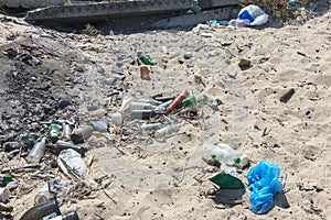 Spilled garbage on beach of big city. Empty used dirty plastic bottles. Dirty sea sandy shore Black Sea. Environmental pollution.