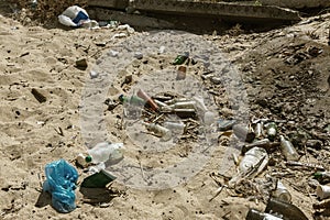 Spilled garbage on beach of big city. Empty used dirty plastic bottles. Dirty sea sandy shore Black Sea. Environmental pollution.