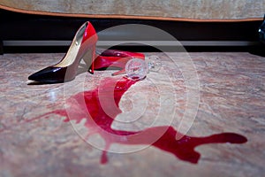 A spilled glass of wine and women`s shoes on the floor