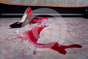 A spilled glass of wine and women`s shoes on the floor photo