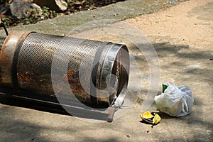 Spilled metal trash can by the side of the park walkway