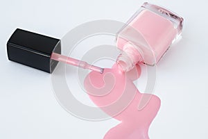Spilled nail polish in glass bottle and brush on white background, pink enamel for french manicure. Beauty product, cosmetic