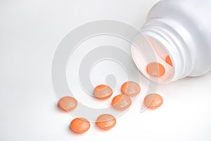 Spilled orange pills from open prescription medication plastic white bottle