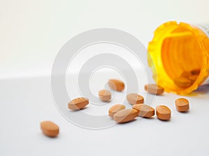 Spilled orange pills on white surface