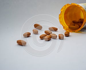 Spilled orange pills on white surface