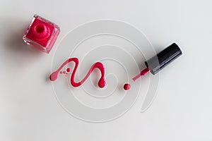 Spilled pink nail polish with bottle and brush on white background