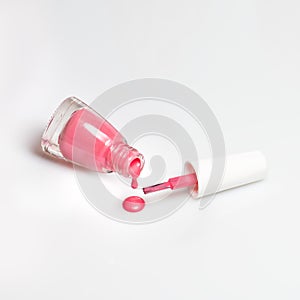 Spilled pink nail polish and brush on white background. Fashion woman still life. Pop female things