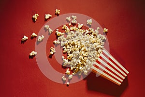 Spilled popcorn on a red background, cinema, movies and entertai photo