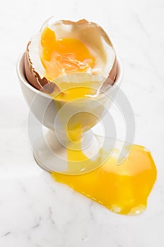 Spilled soft boiled egg in an egg cup