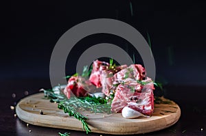 Spilling herbs on meat with bones and rosemary