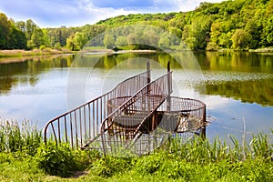 Spillway with metal railing on forest lake. Goloseevo, Kiev, Ukraine