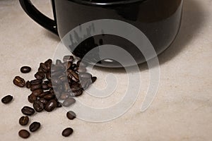 Spilt coffee beans beside a black mug
