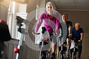 Spin together to win together. a group of seniors having a spinning class at the gym.