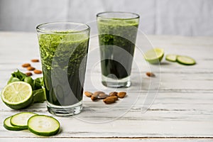 Spinach and almond smoothies against white wooden background.