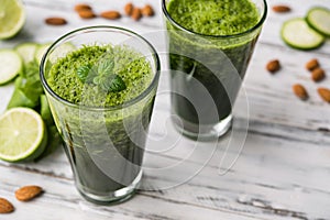 Spinach and almond smoothies against white wooden background.