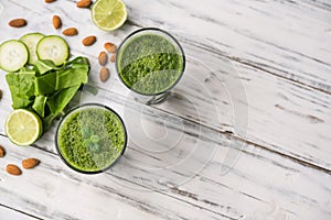 Spinach and almond smoothies against white wooden background.