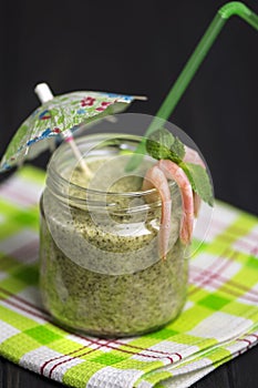 Spinach cream soup with shrimp in a glass jar