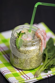 Spinach cream soup with shrimp in a glass jar
