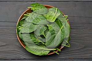 spinach leaves in bowl on dark wooden table top view
