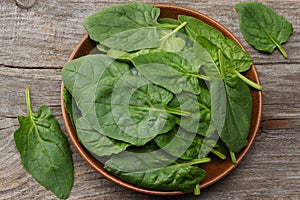 Spinach leaves in bowl on old wooden table top view