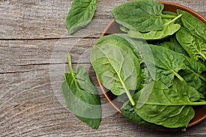 spinach leaves in bowl on old wooden table top view