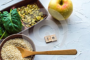 Spinach, pumpkin seeds, sesame, apple and one wood spoon on a white background. microelement FE. Close-up