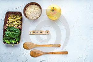 Spinach, pumpkin seeds, sesame, apple and two wooden spoons on a white background. Anemia concept. Close-up