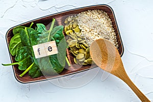 Spinach, pumpkin seeds, sesame and one wood spoon on a white background. microelement FE. Close-up