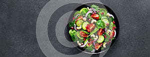 Spinach salad with fresh cucumbers, tomato, onion, pomegranate, sesame seeds and cashew nuts on black background. Healthy vegan fo