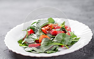 Spinach salad with pepper and tomatoes in white plate
