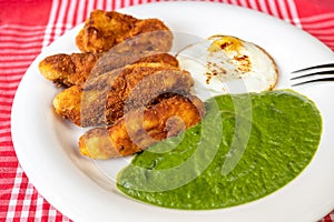 Spinach sauce, fried potato croquettes and fried egg on plate