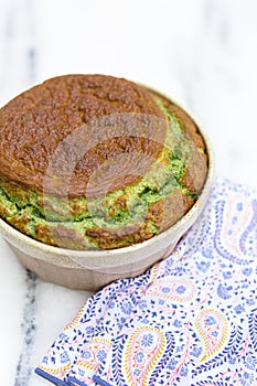Spinach souflÃ© in ramekin with patterned napkin