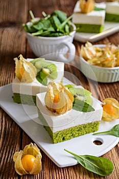 Spinach sponge cake topped with curd mixed with whipped cream, decorated with golden berries and kiwi slices