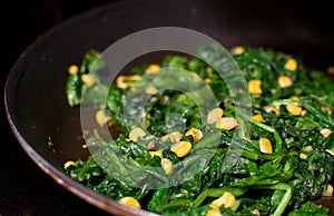 Spinach wilted and fried corn on skillet