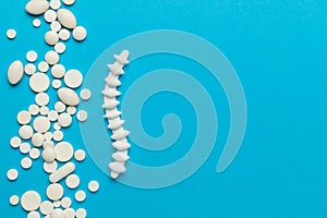 Spine with pills on a blue background. Back pain and treatment. Inflammation in the lower back