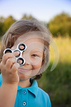 Spinner in the hand of a child smiling in the nature on a summer