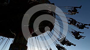 Spinning carousel with riding people on blue sky background