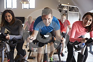 Spinning class on exercise bikes at a gym looking to camera