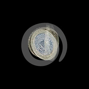Spinning coin in stroboscopic light on black background. Two pounds coin