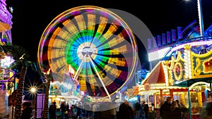 Spinning ferris wheel in motion on funfair. An abstract blurred background object image of ferris wheel at night
