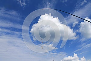 Spinning, fishing line and sinker on a white cloud